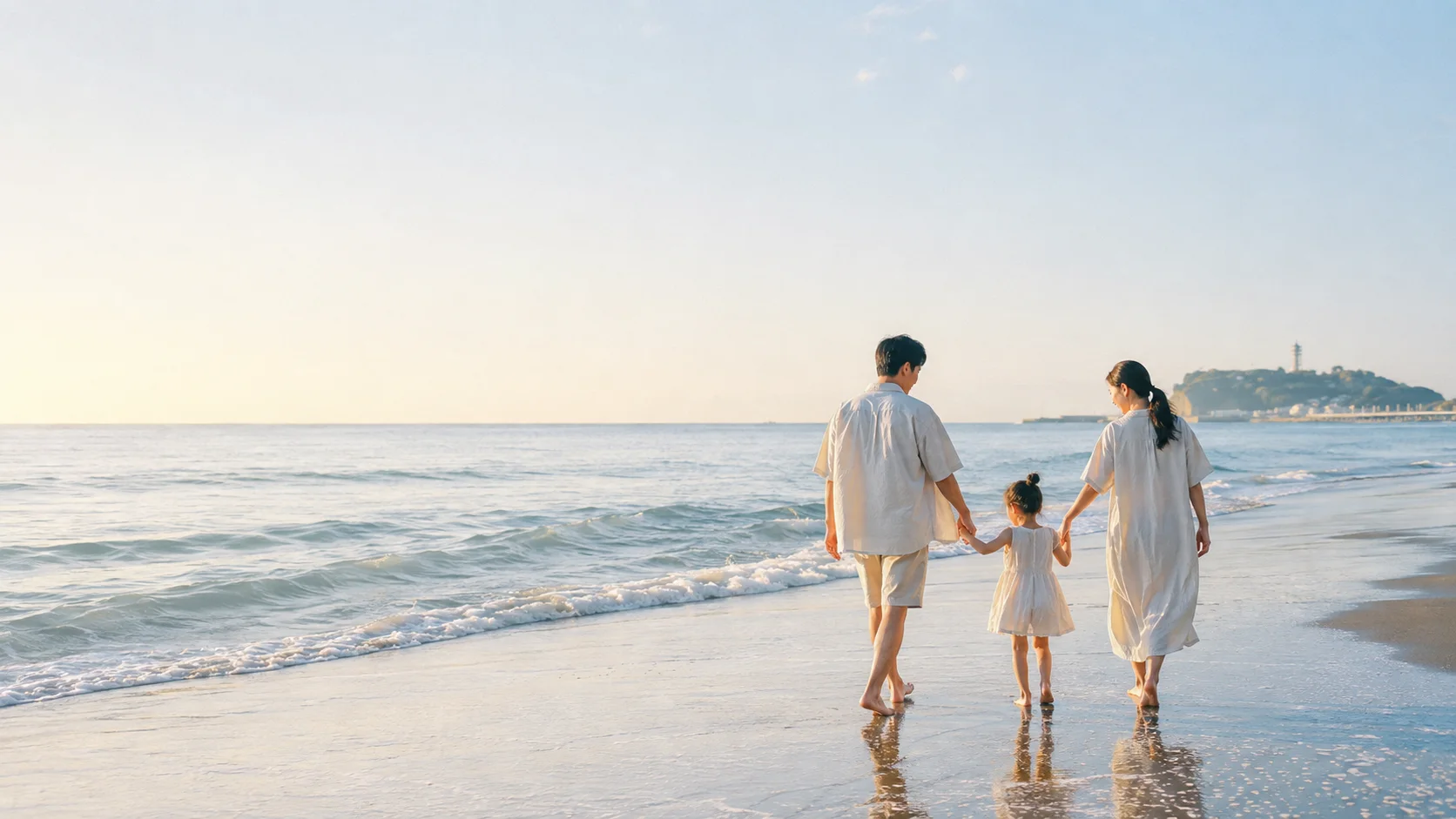 朝の湘南の海辺を歩く家族